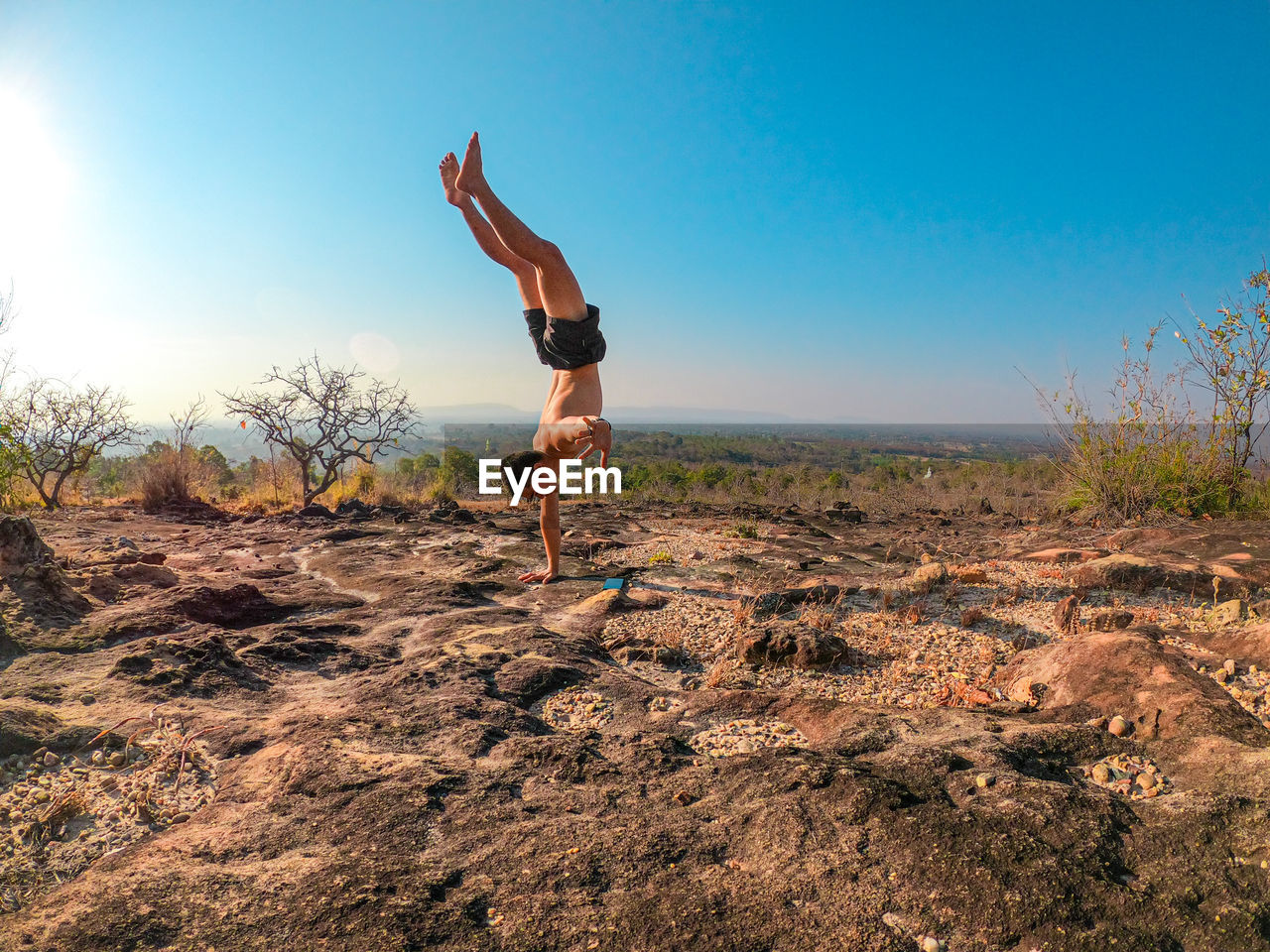 FULL LENGTH OF MAN CLIMBING ON LAND AGAINST SKY