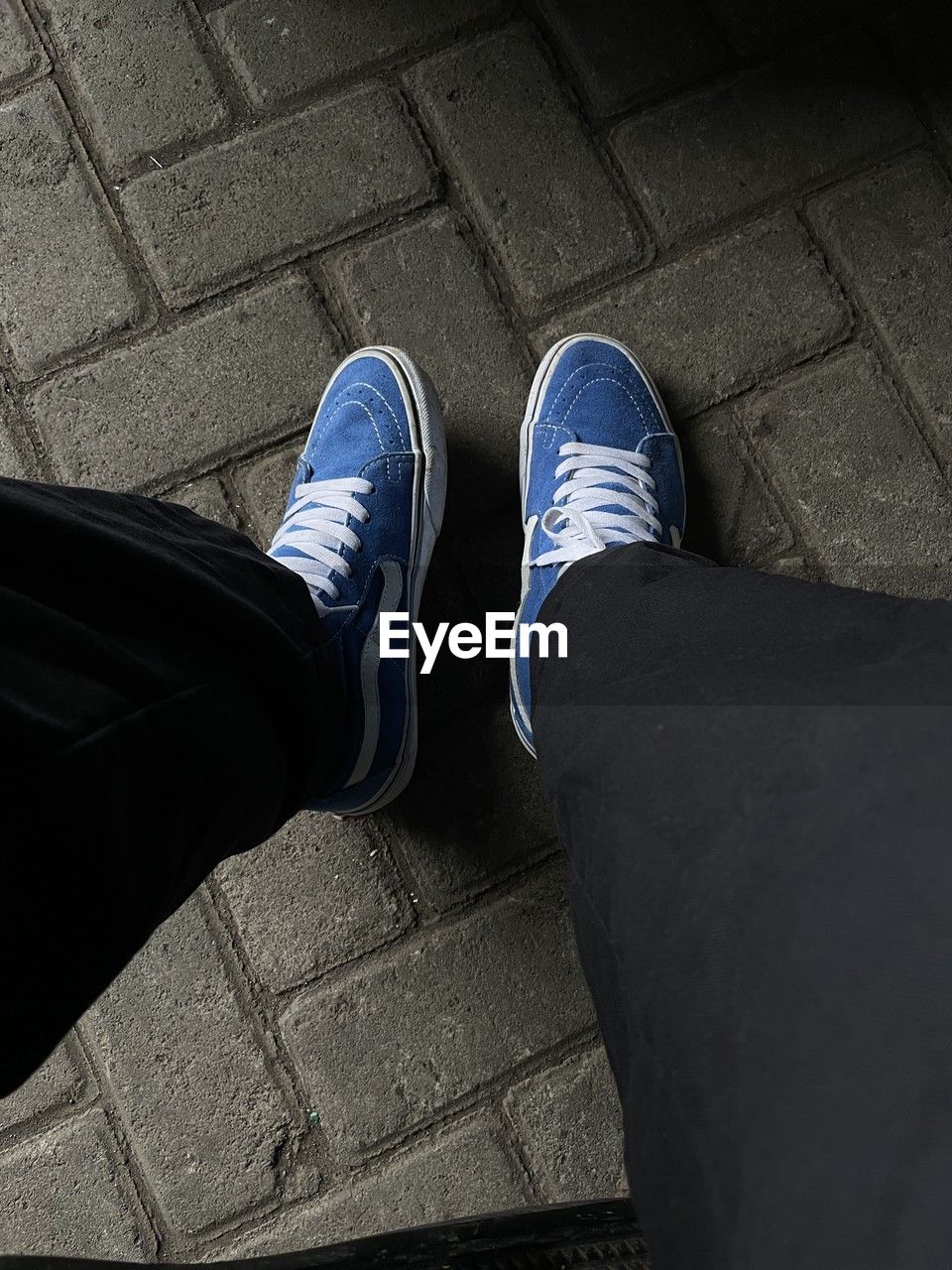 black, low section, shoe, human leg, blue, white, one person, limb, footwear, human limb, high angle view, standing, lifestyles, footpath, personal perspective, men, adult, city, darkness, street, clothing, day, leisure activity, casual clothing, outdoors, human foot, directly above, jeans, sneakers, sidewalk