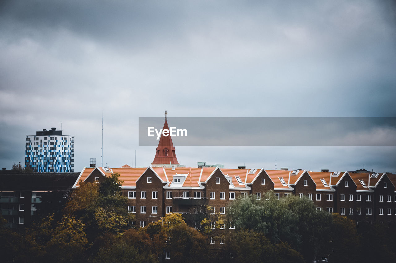 Buildings in city against cloudy sky