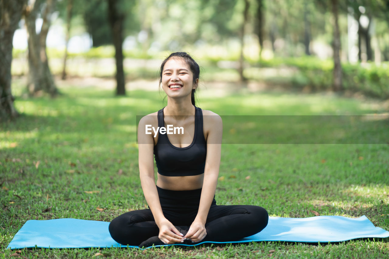 Smiling young woman sitting on plant in park