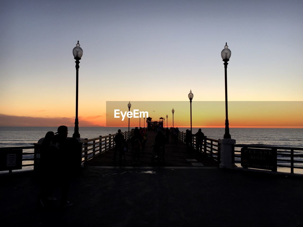 Silhouette people on pier during sunset