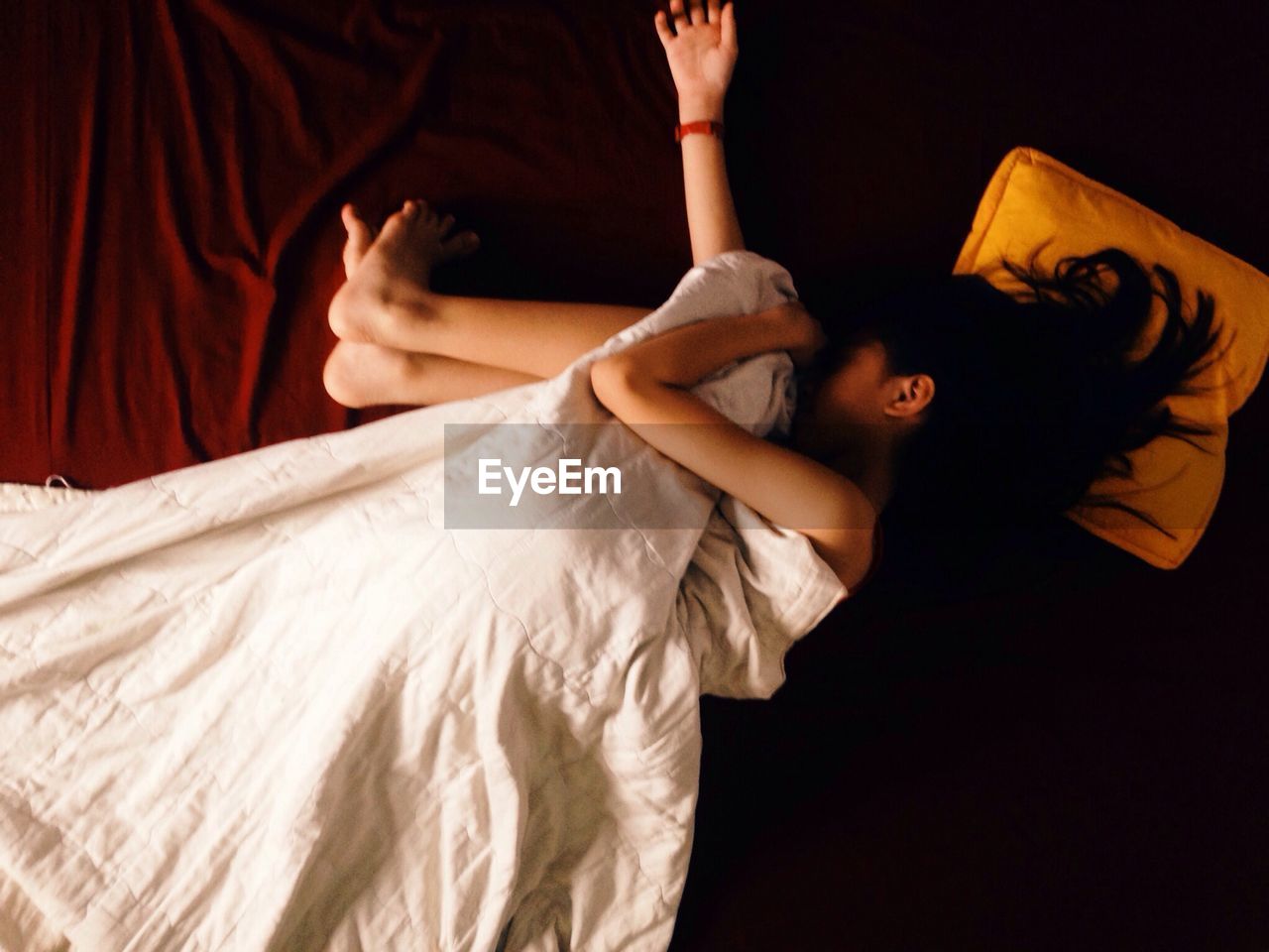 Directly above view of girl sleeping on bed with blanket