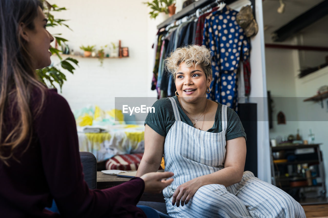 Mid adult woman listening to friend talking in living room at home