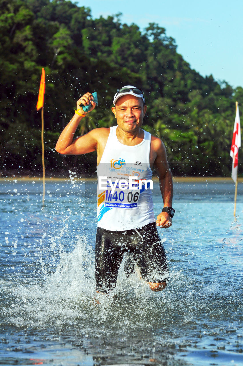 PORTRAIT OF SMILING MAN HOLDING SPLASHING WATER