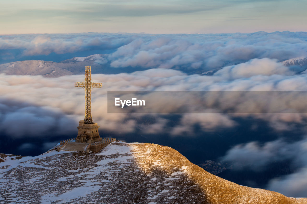 Religious cross on mountain by cloudscape