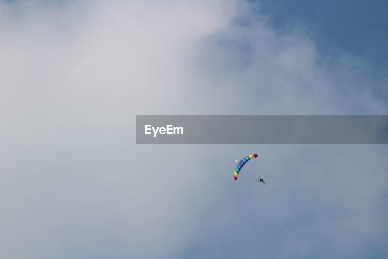 Low angle view of person paragliding against cloudy sky