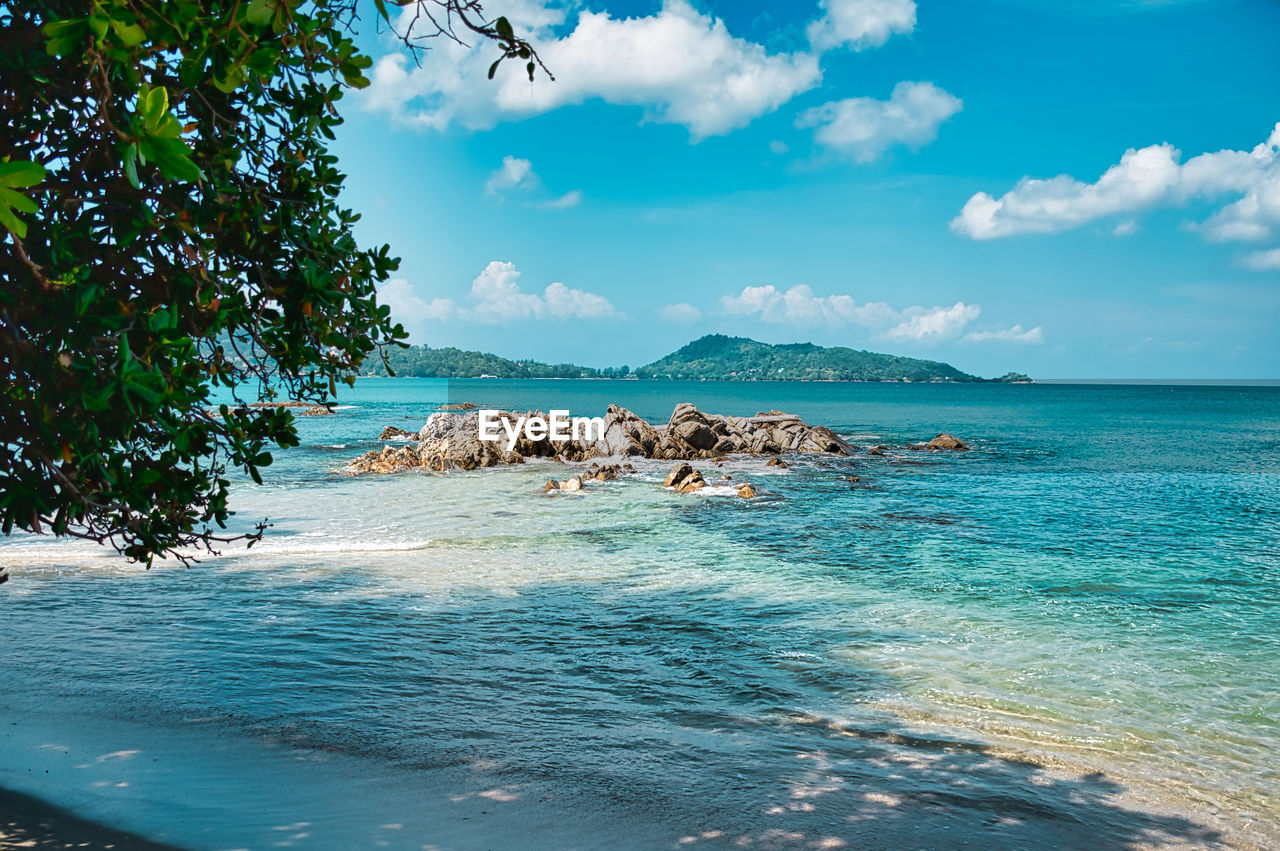 Empty, calm sandy crescent kalim bay, beach with turquoise blue clear water and cirrus cloudy sky