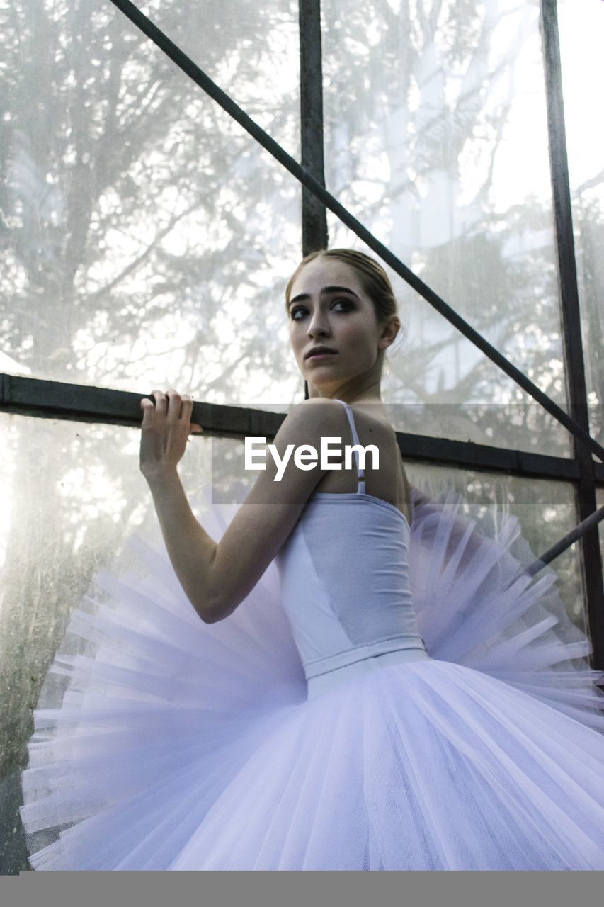 Ballet dancer standing by glass window