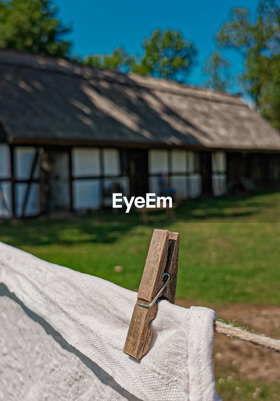 Clothespin over laundry on line against house and trees