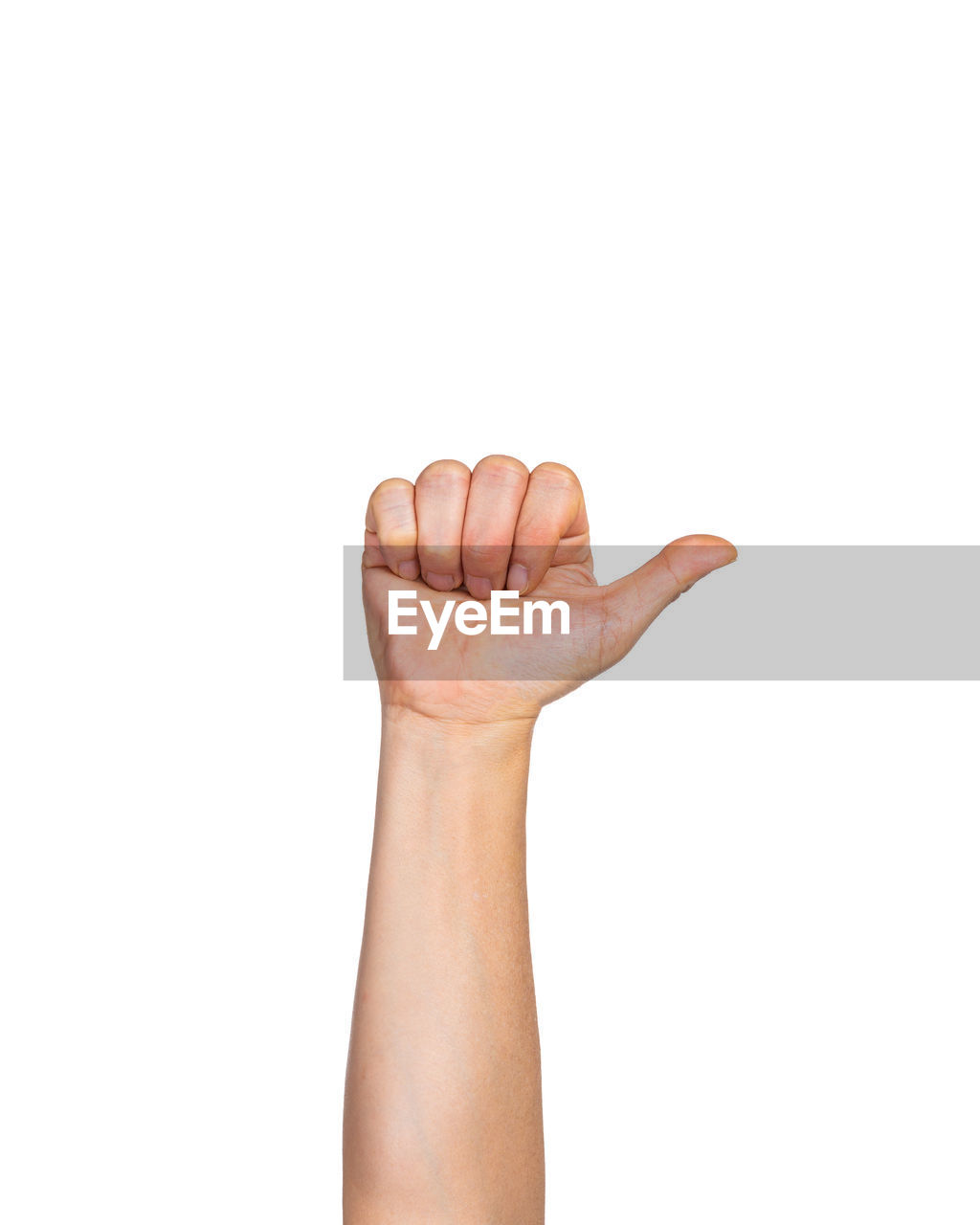 Close-up of cropped hand showing thumbs up sign against white background