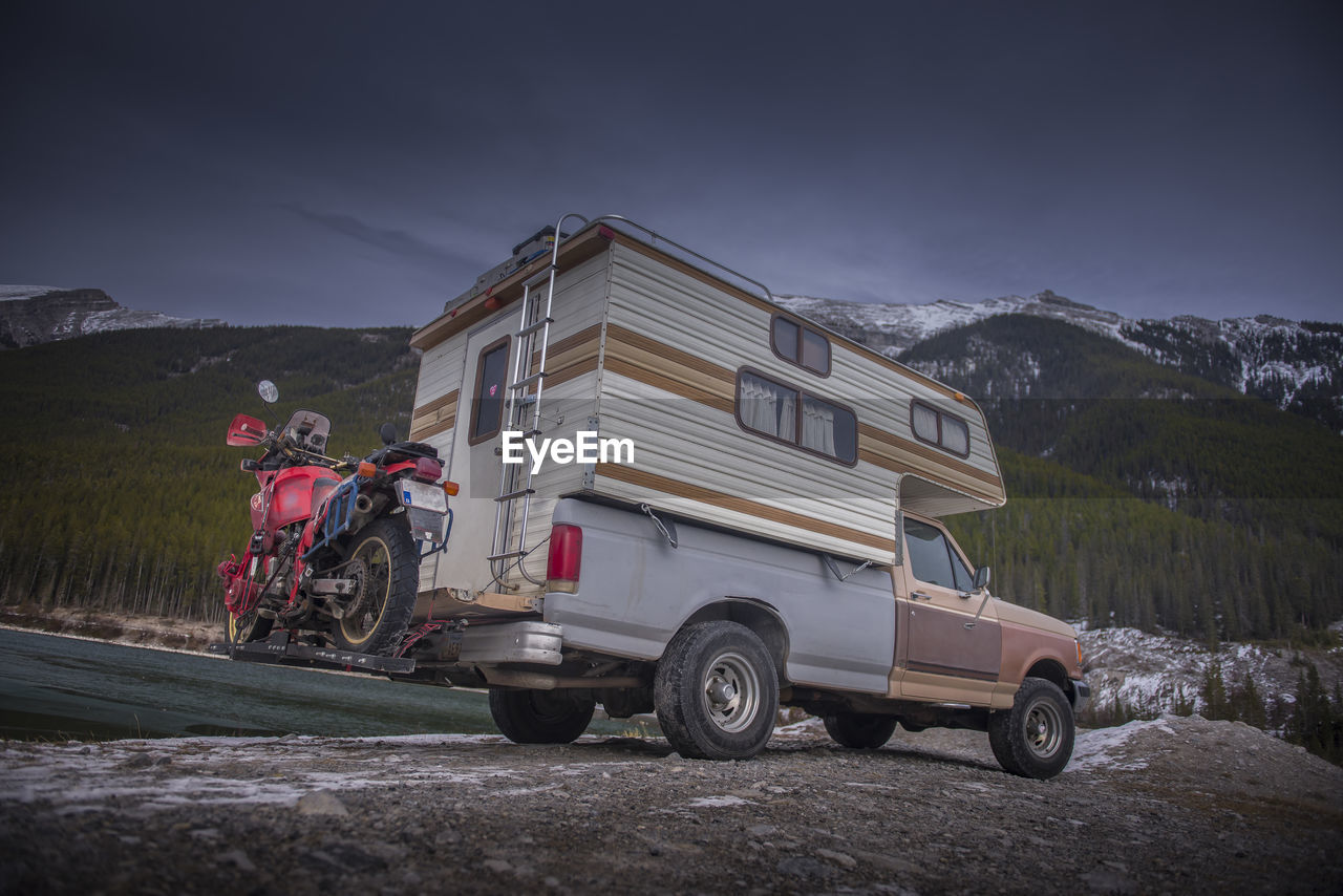 Camper truck with touring motorcycle in spray lakes reservoir