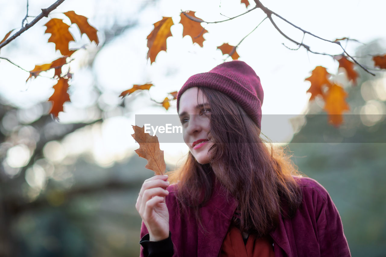 Portrait of young woman in park during autumn