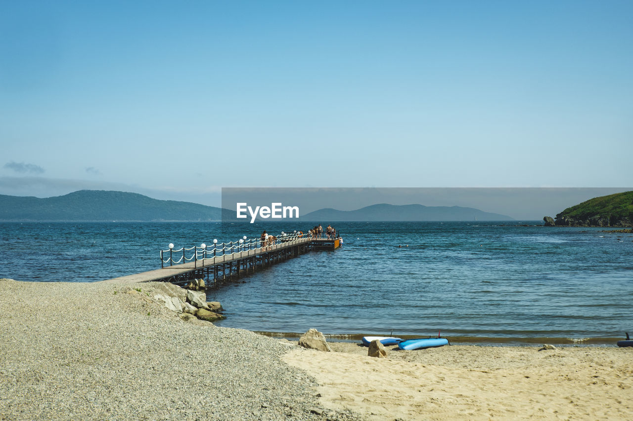 Long pier in clear blue sea on sandy beach. summer vacation by sea