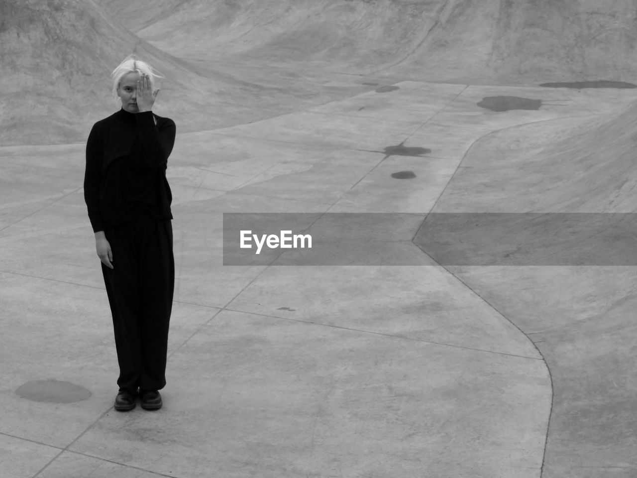 Woman in black standing on the grey concrete in monochrome 