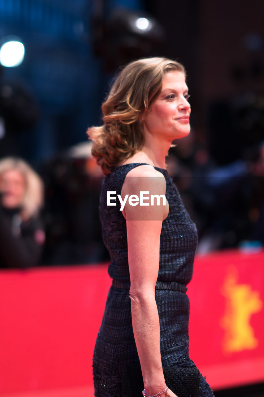 WOMAN LOOKING AWAY WHILE STANDING AT RED INDOORS