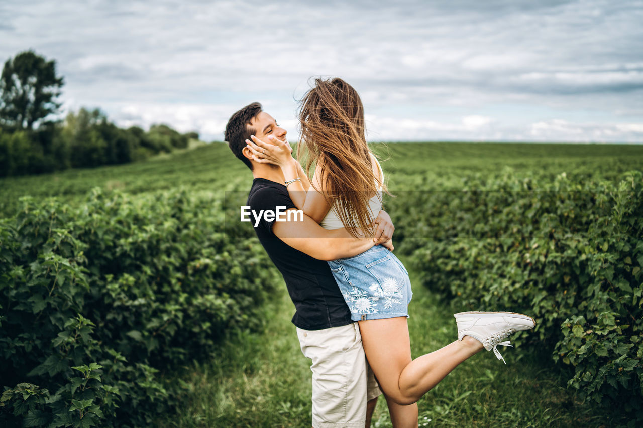 Young cuple standing on field against sky