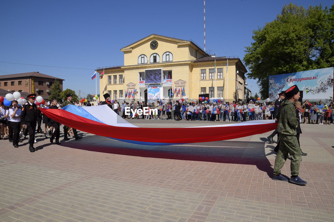 PEOPLE ON STREET AGAINST BUILDING IN CITY