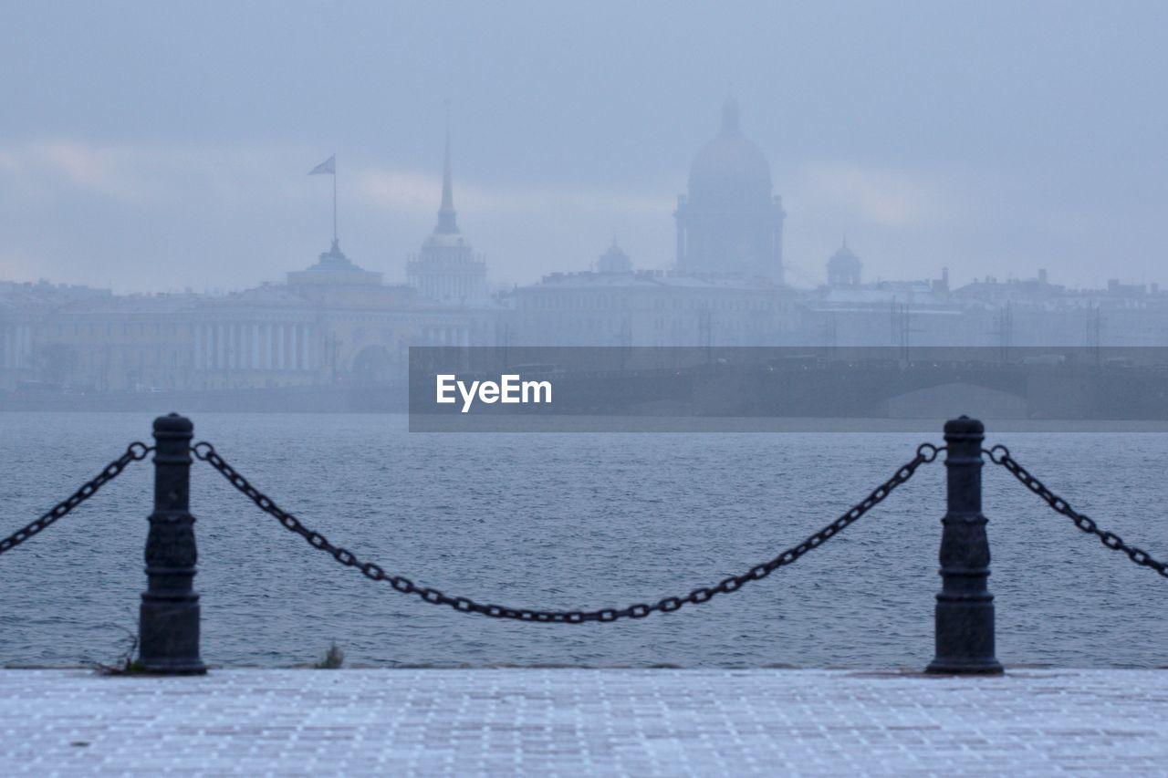 Scenic view of neva river against buildings in foggy weather