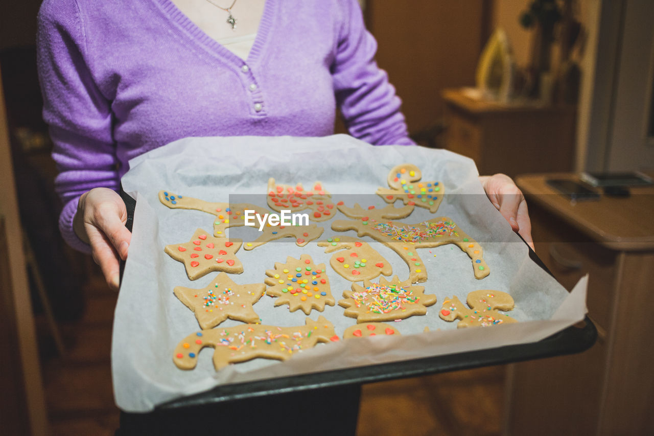 Midsection of woman holding cookies in tray