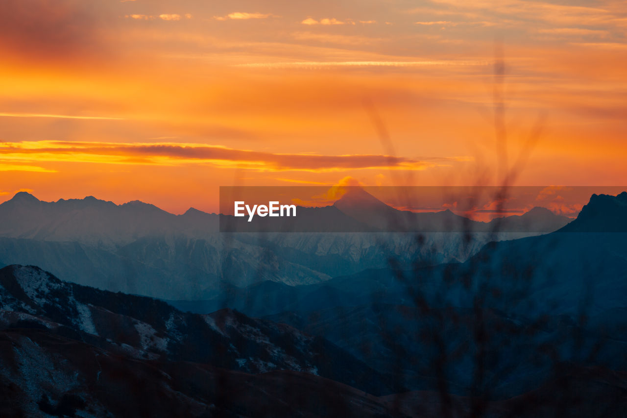 Scenic view of mountains against orange sky