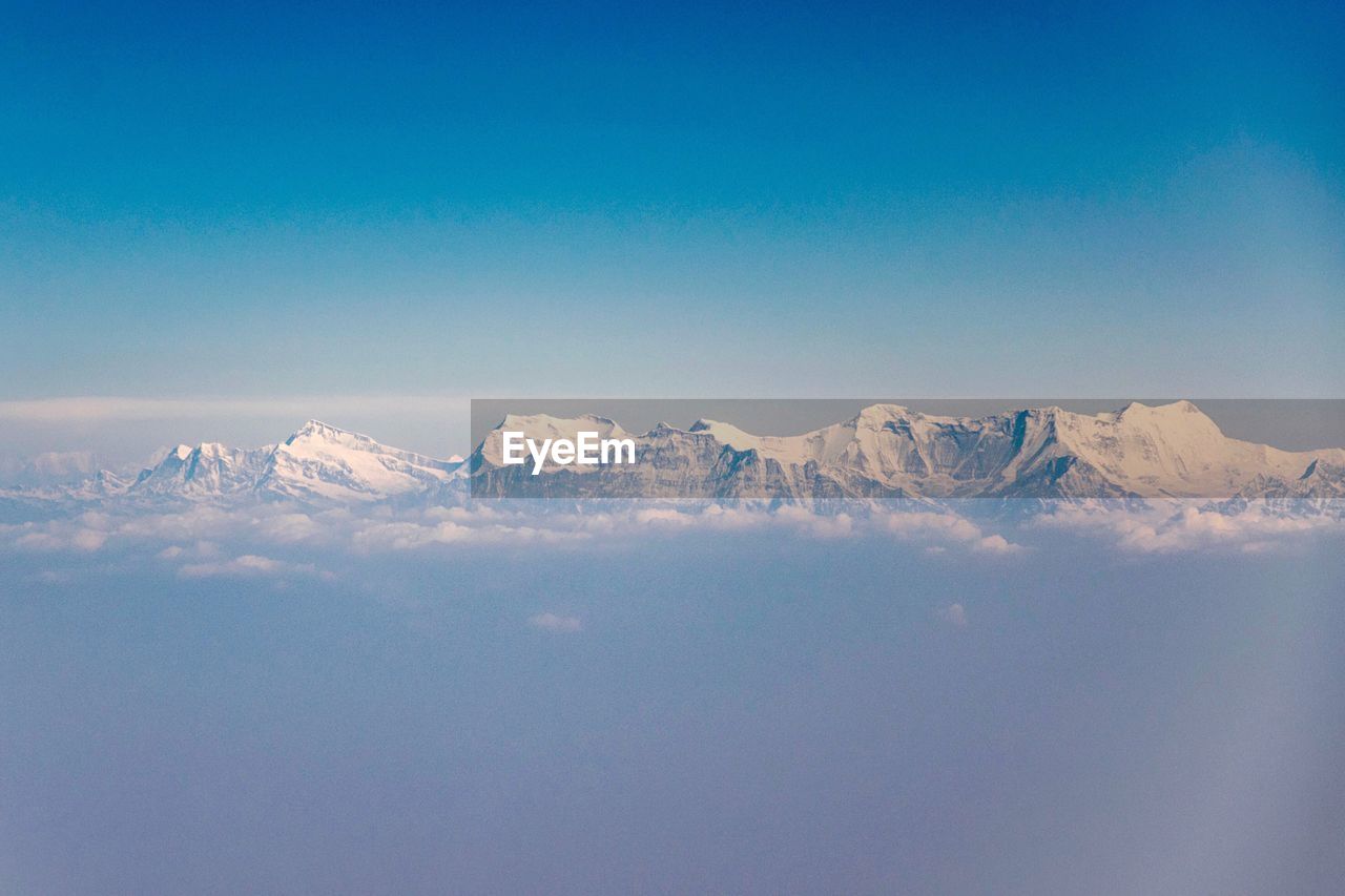 Scenic view of snowcapped mountains against clear blue sky