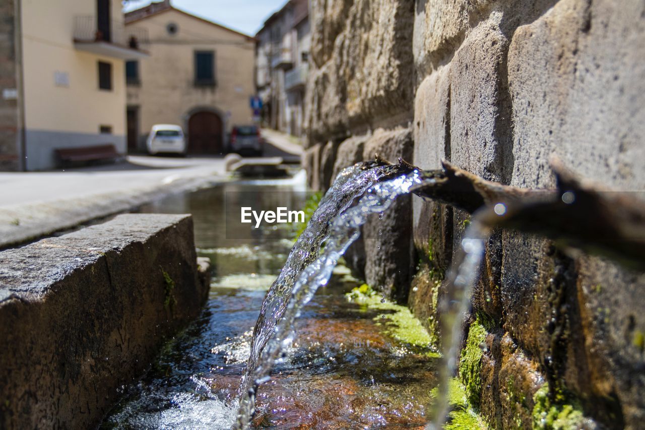 CLOSE-UP OF FOUNTAIN AGAINST BUILDINGS