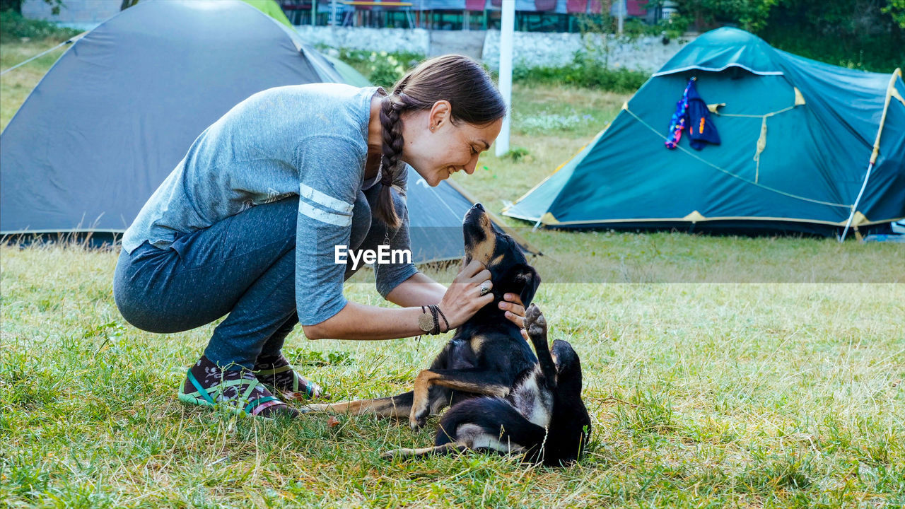 Woman playing with dog on grassy land at campsite