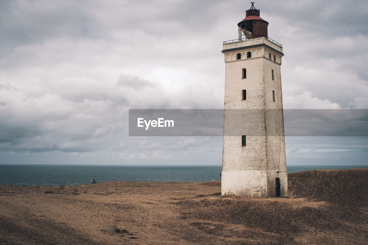 Lighthouse by sea against sky