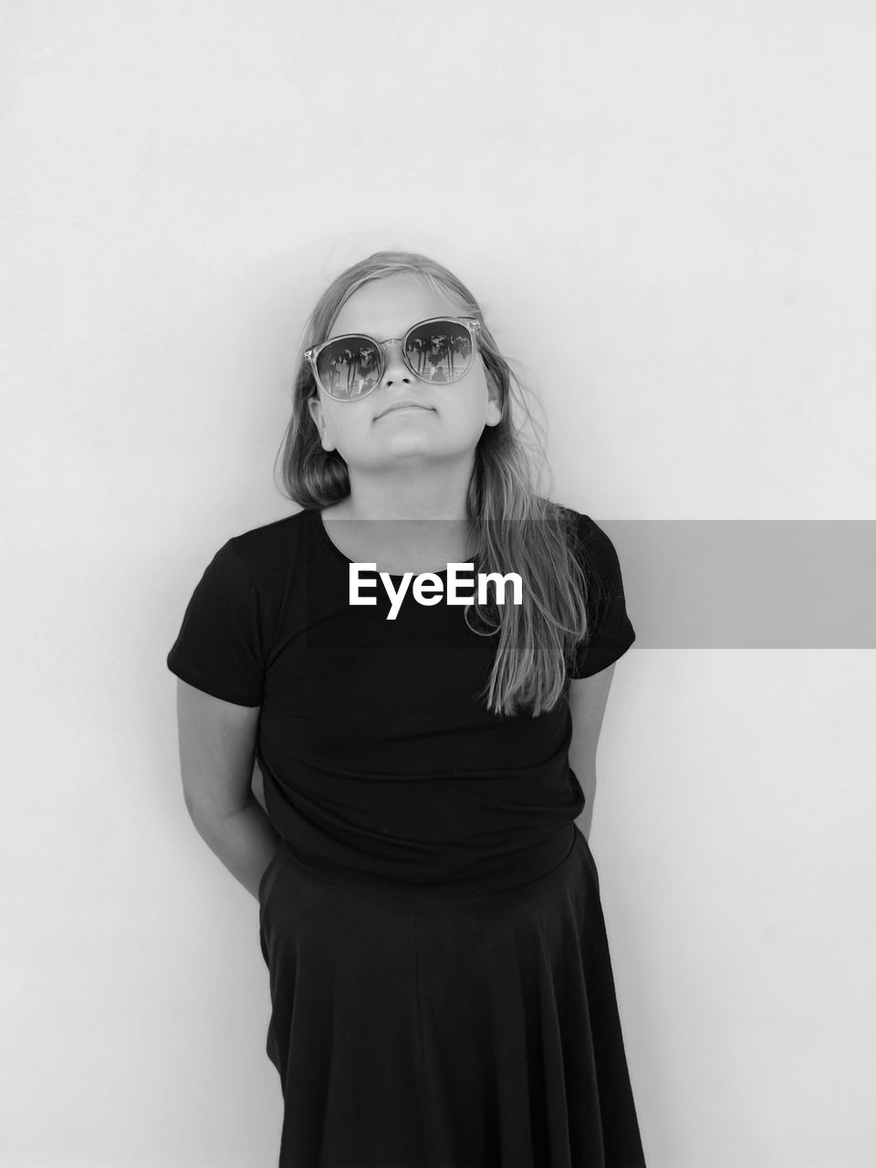 Portrait of young woman wearing sunglasses against white background