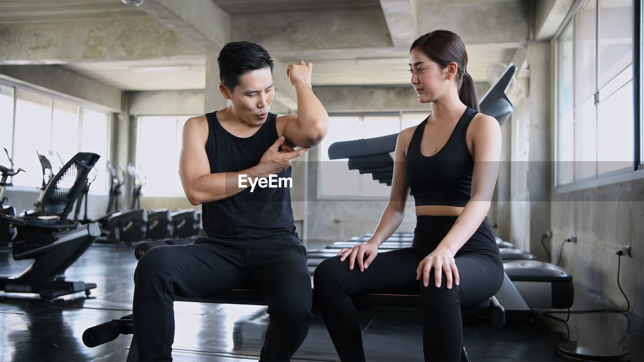 Instructor showing bicep to woman at gym