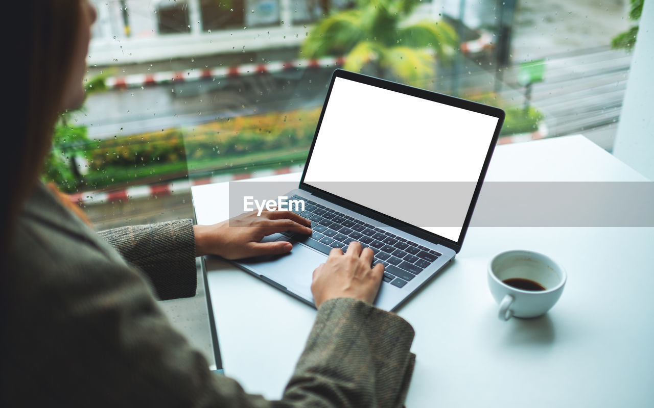 cropped hands using laptop at table
