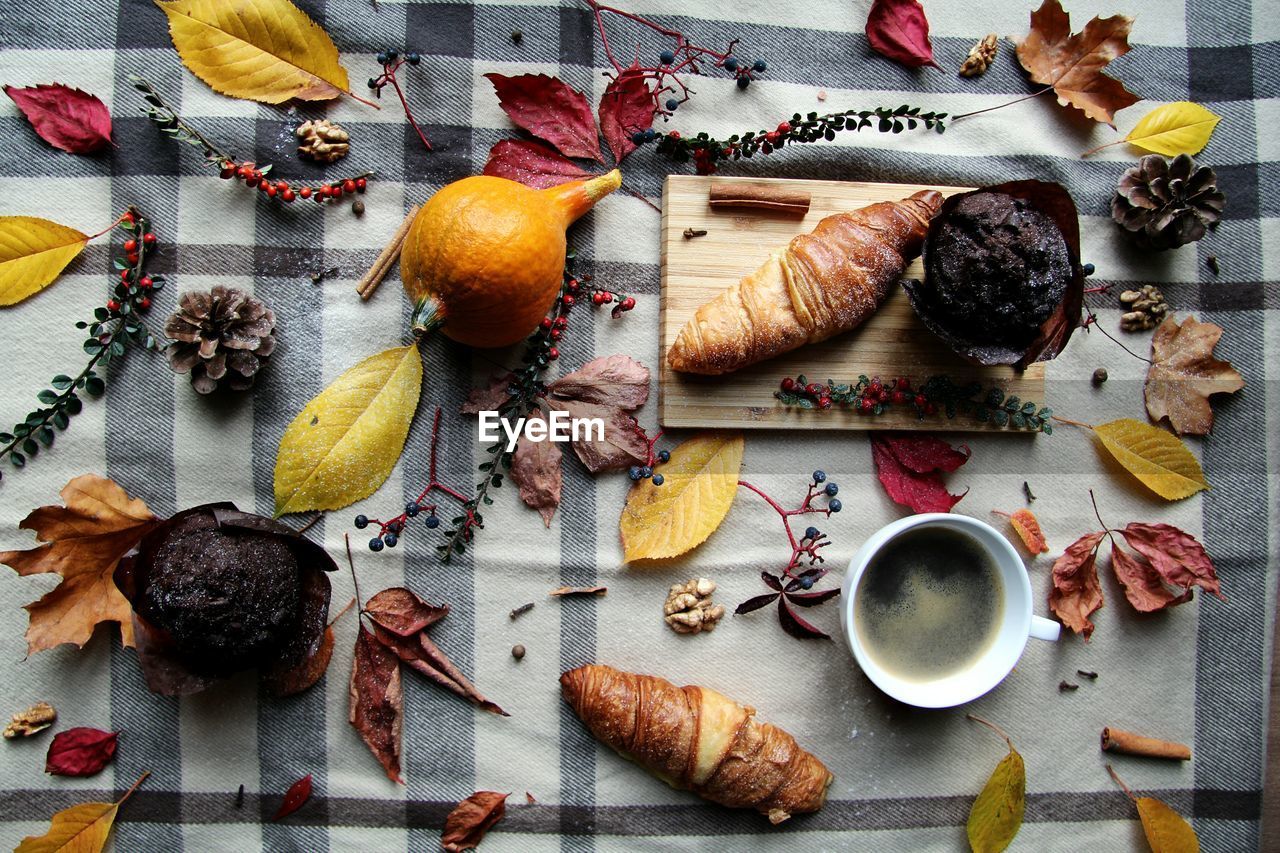 High angle view of coffee with various food and autumn leaves on table