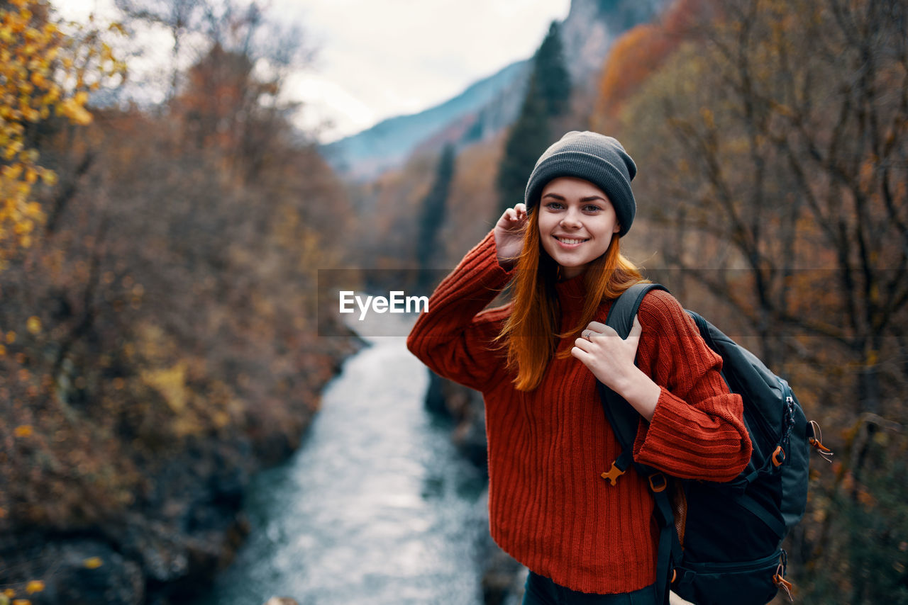 YOUNG WOMAN STANDING BY TREE DURING WINTER