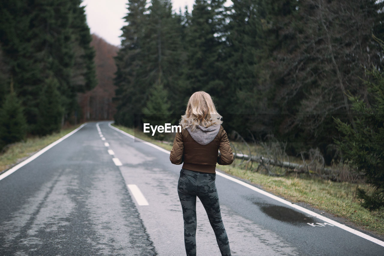 Rear view of woman standing on road