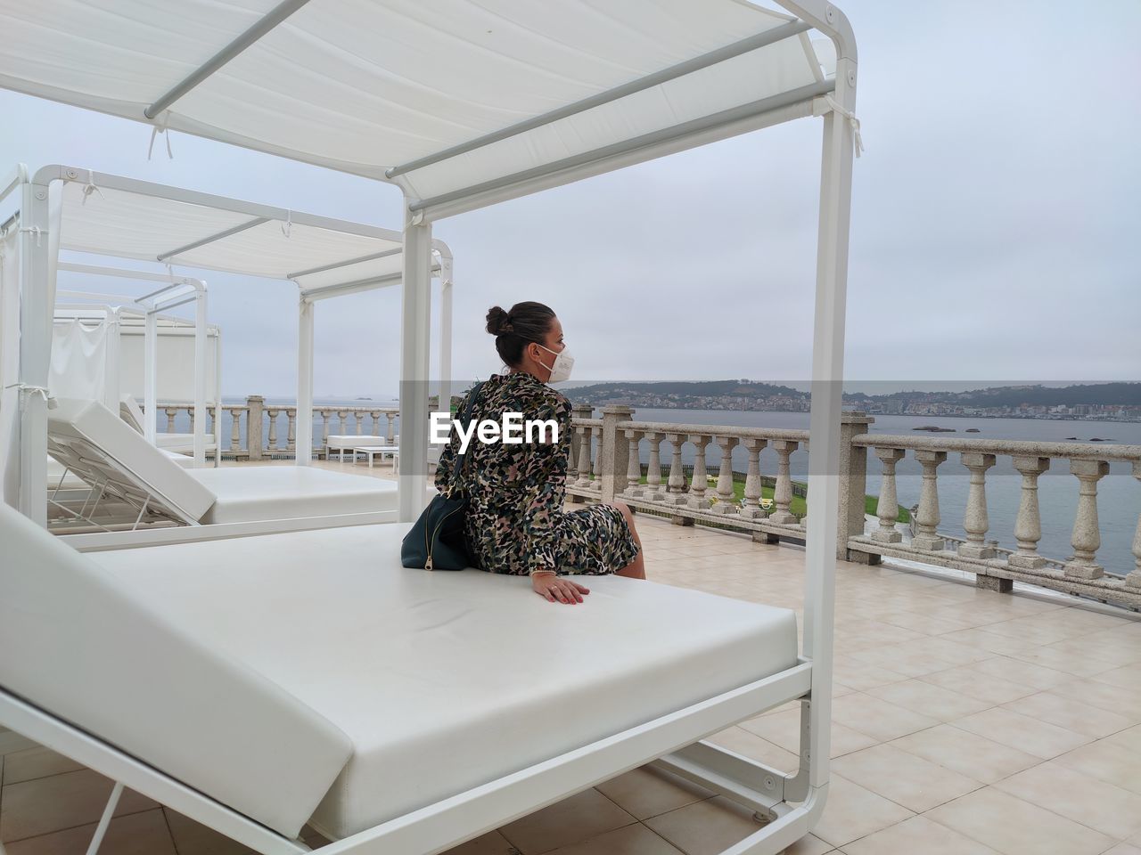 Full length of woman sitting on railing against sea