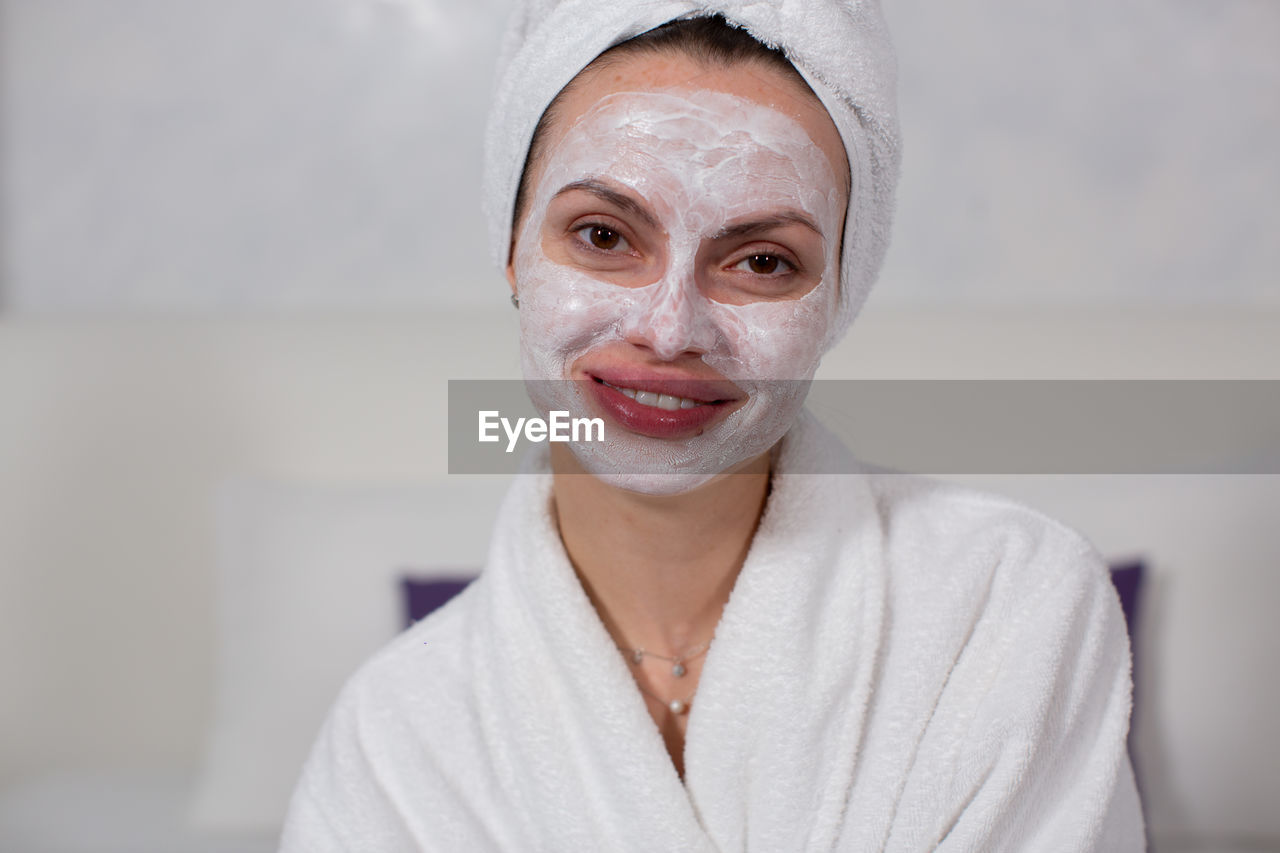 Young woman with facial mask on face at home