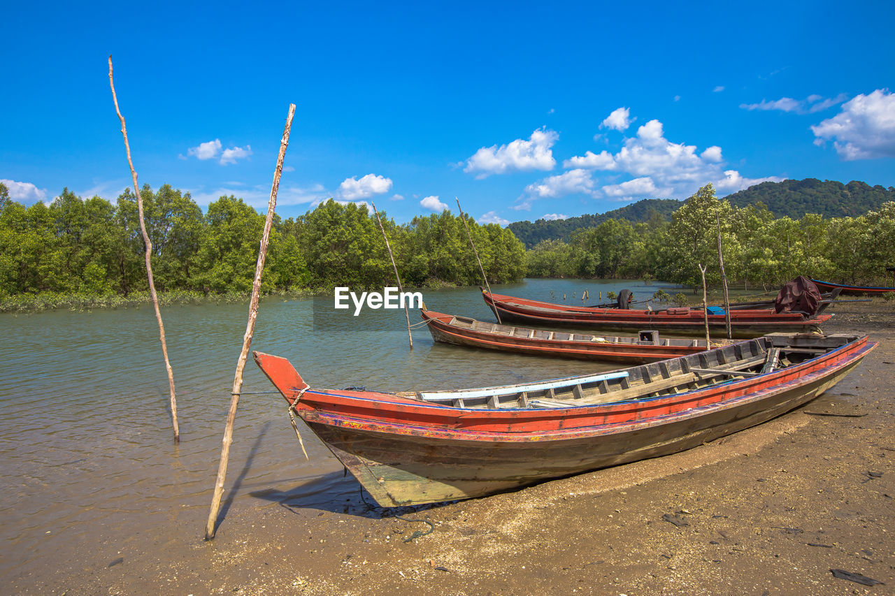 BOATS MOORED ON SHORE AGAINST SKY