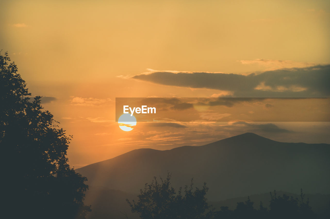 Scenic view of silhouette mountains against orange sky