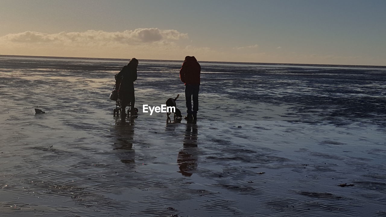 SILHOUETTE MEN ON BEACH AGAINST SKY AT SUNSET