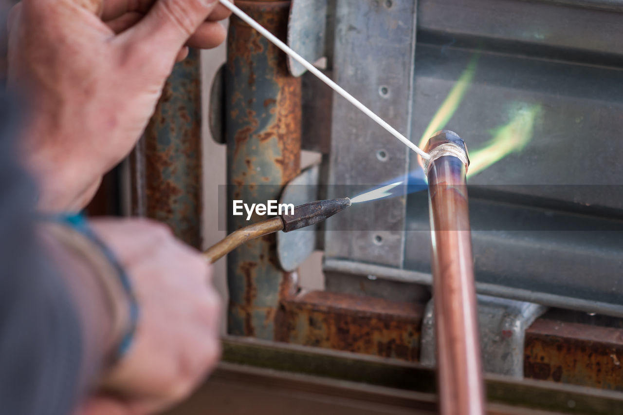 Cropped hands burning metal in workshop