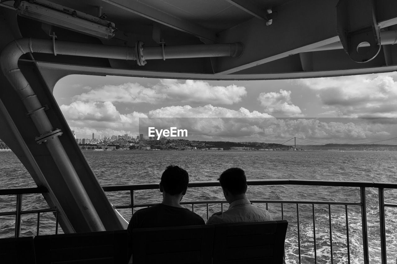 Rear view of men traveling in ferry boat