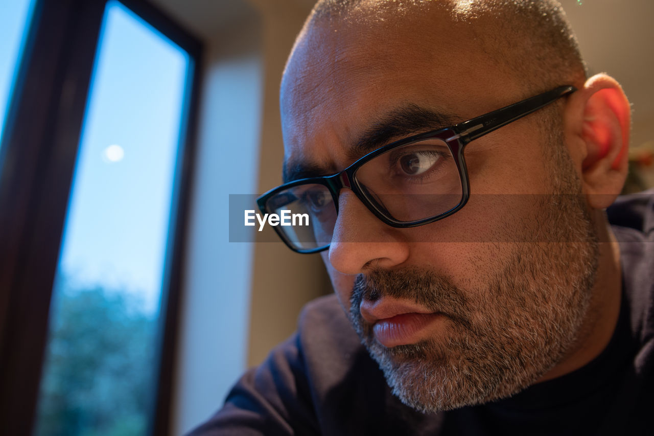 Close-up of man wearing eyeglasses at home