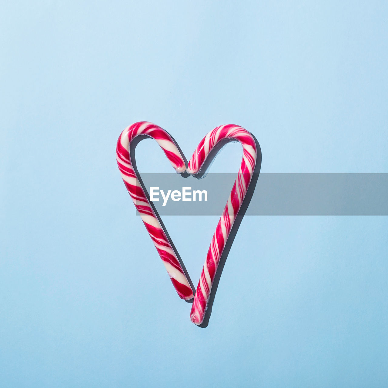 Heart shape candy cane over blue background