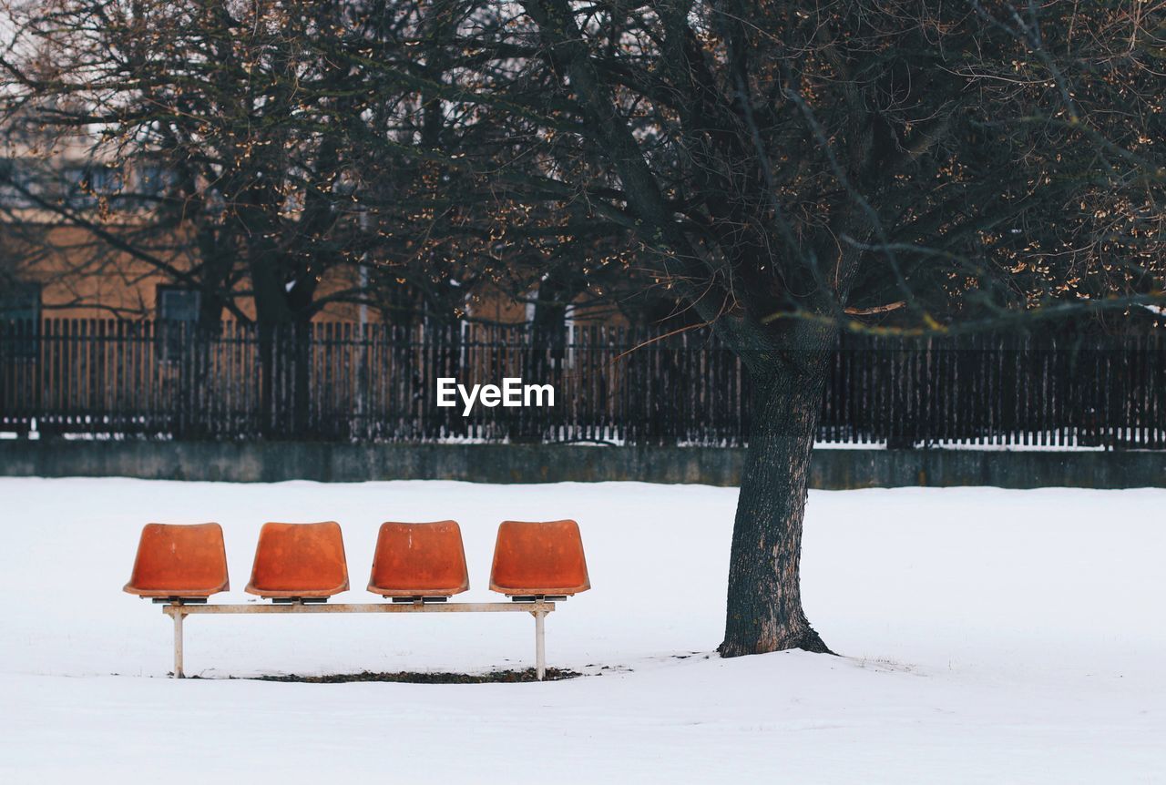 Empty chairs on snow covered field during winter