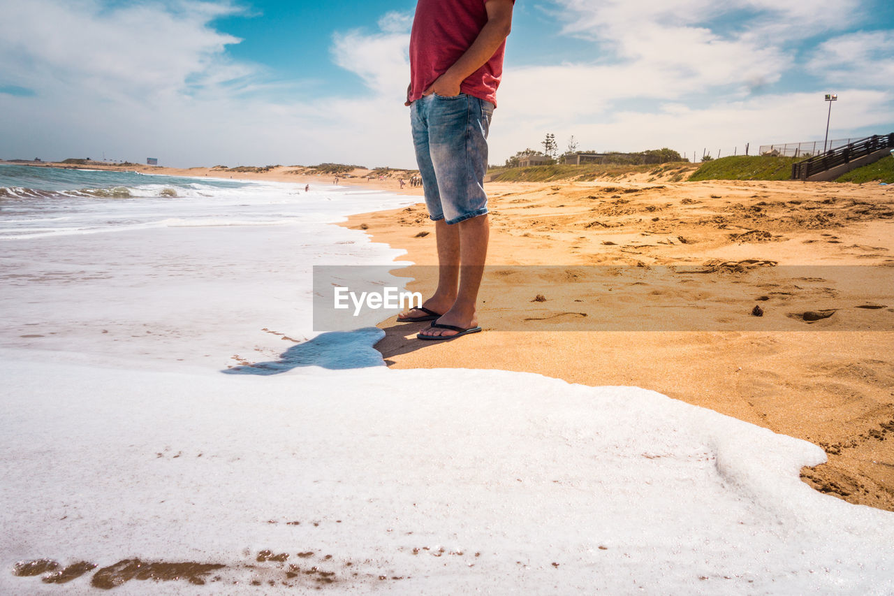 Low section of man standing on beach