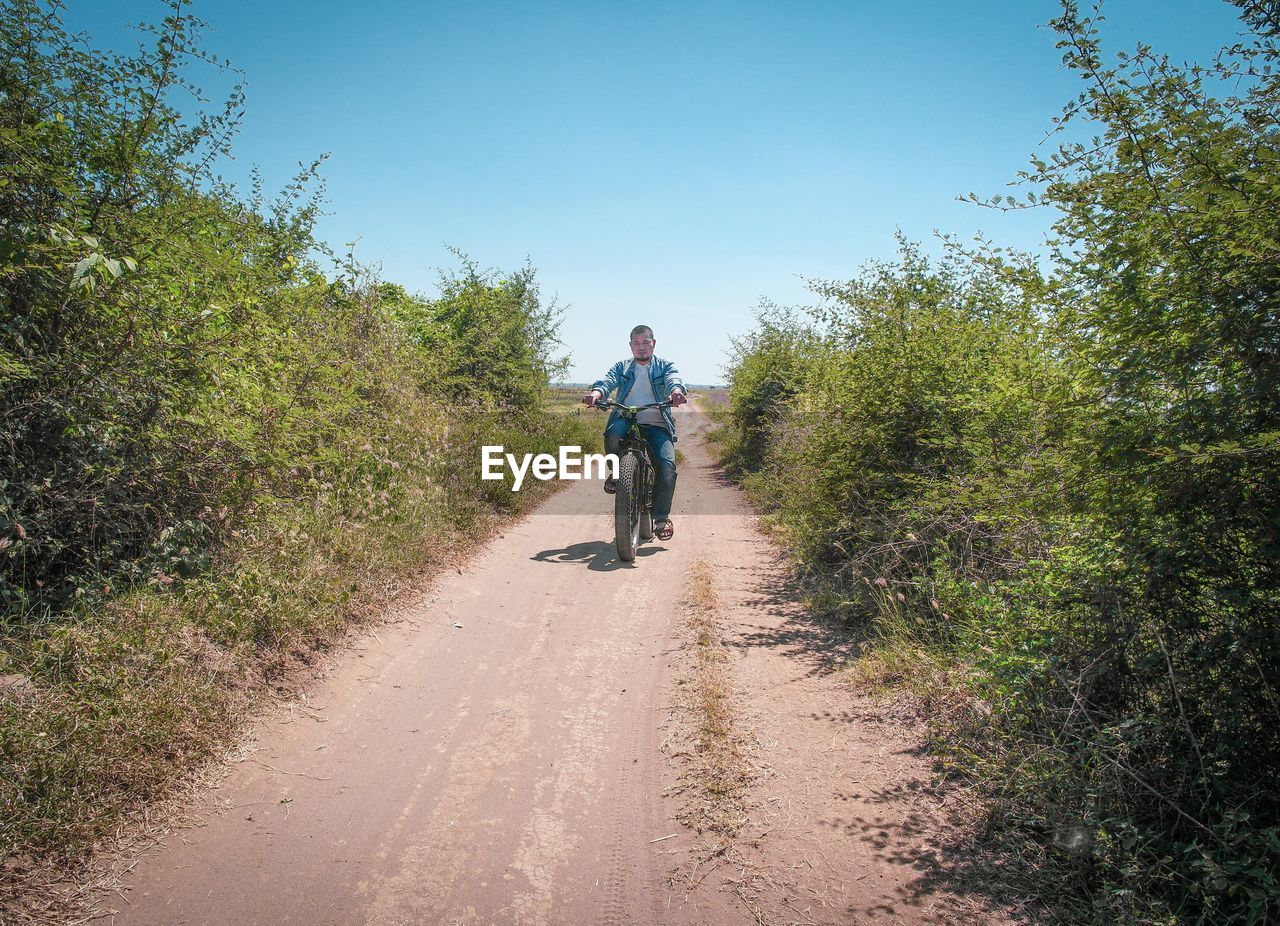 Rear view of man riding bicycle on road