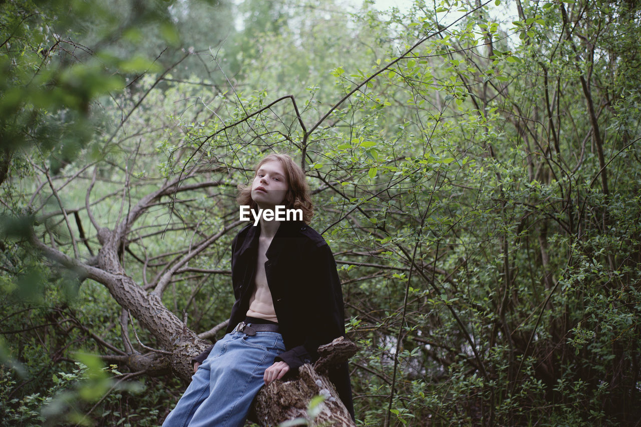 YOUNG WOMAN IN FOREST AGAINST TREES