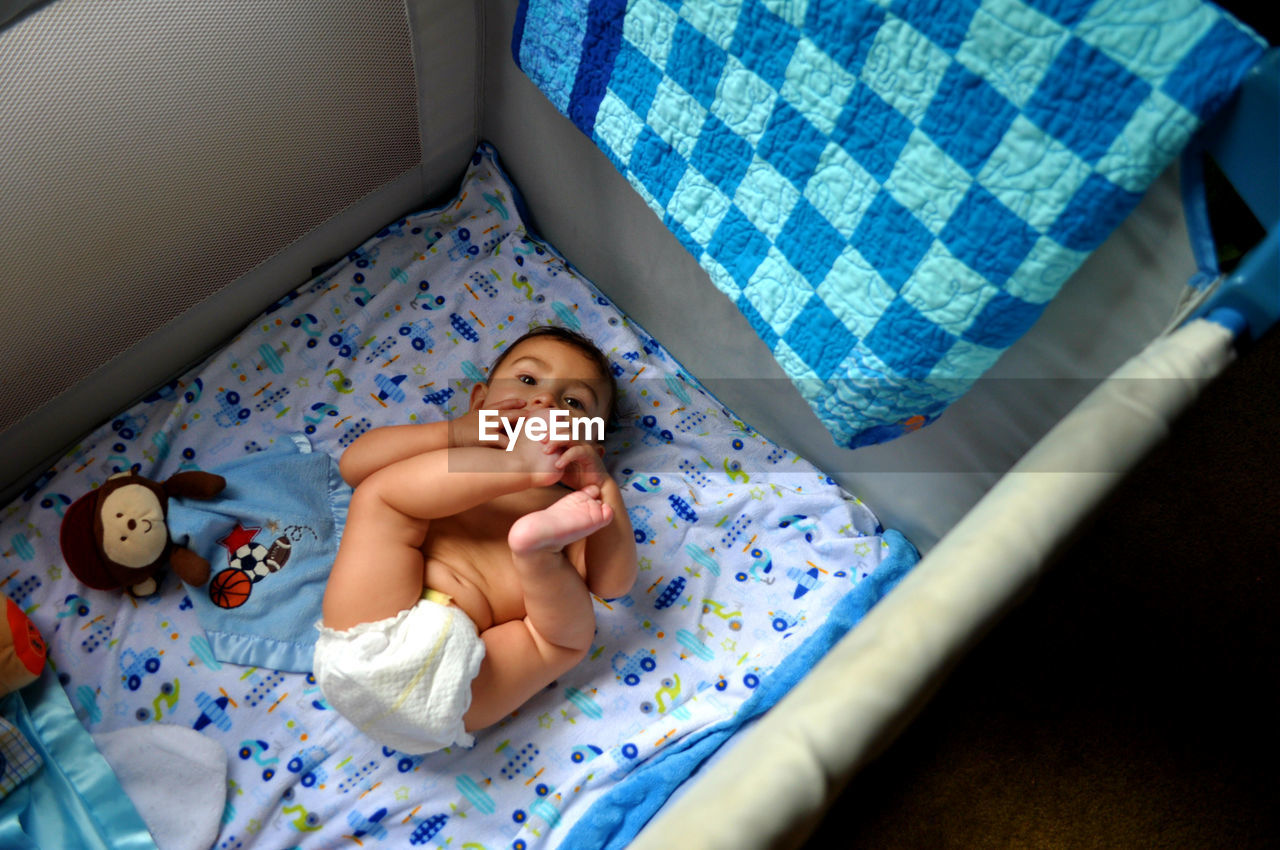 High angle view of cute baby boy lying in crib at home