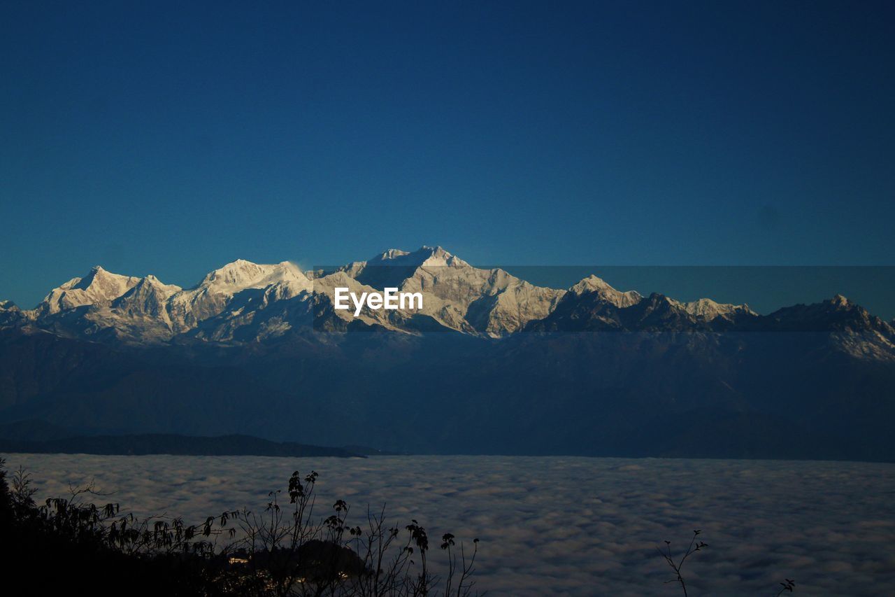 Scenic view of snowcapped mountains against clear blue sky