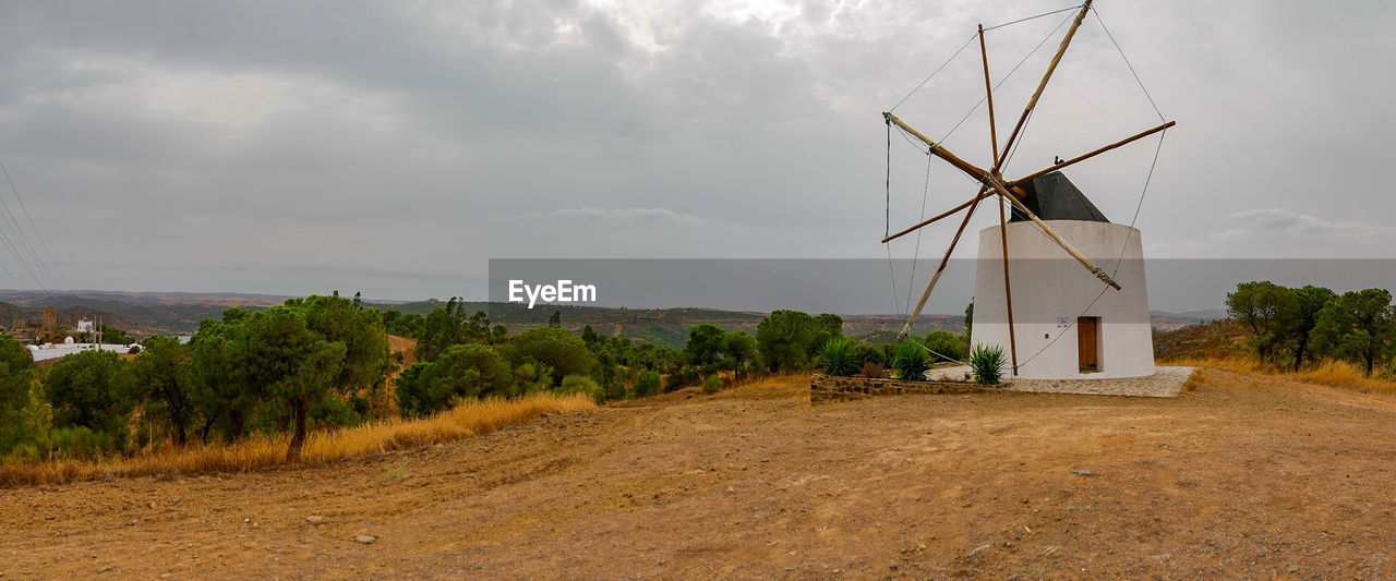 WINDMILLS ON FIELD AGAINST SKY